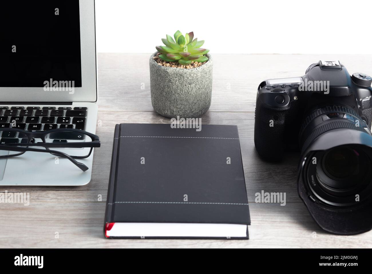 La postazione di lavoro per fotografi con macchina fotografica, computer portatile, occhiali sul tavolo di legno Foto Stock