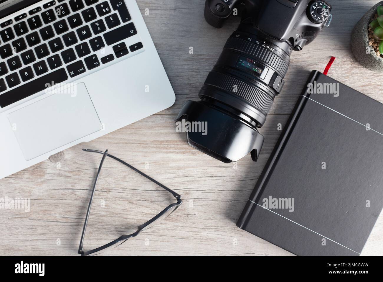 La postazione di lavoro per fotografi con macchina fotografica, computer portatile, occhiali sul tavolo di legno Foto Stock