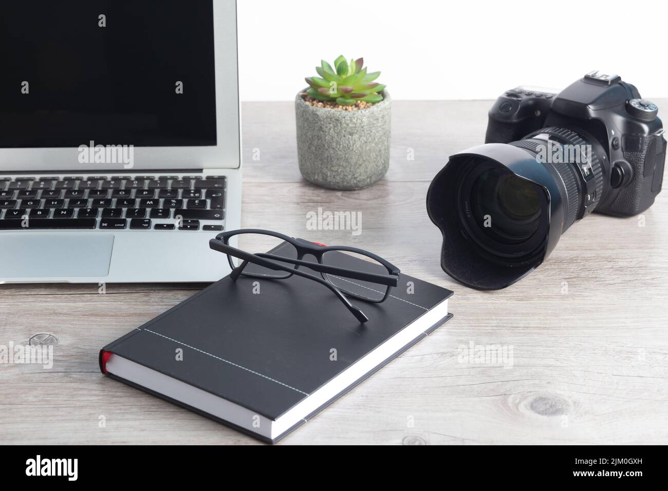 La postazione di lavoro per fotografi con macchina fotografica, computer portatile, occhiali sul tavolo di legno Foto Stock
