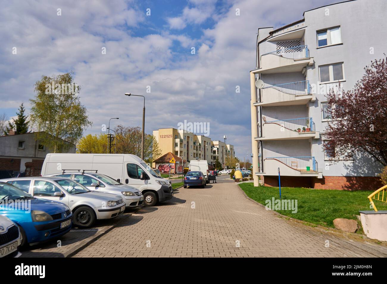 Una fila di auto parcheggiate nei parcheggi di fronte ad un edificio di appartamenti a Poznan, Polandvv Foto Stock