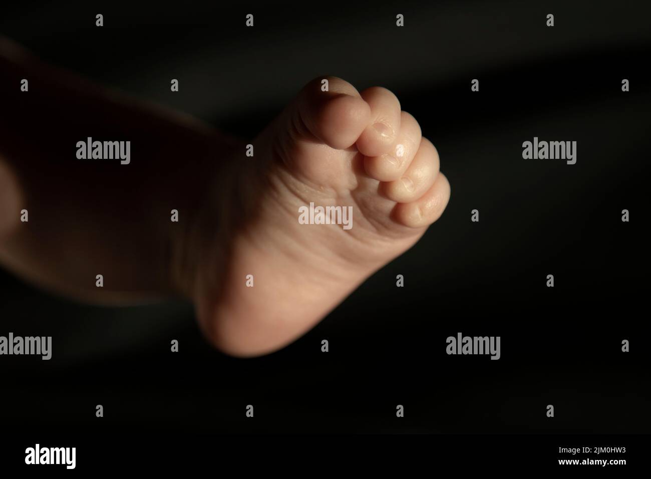 Piede del bambino e sfondo scuro Foto Stock