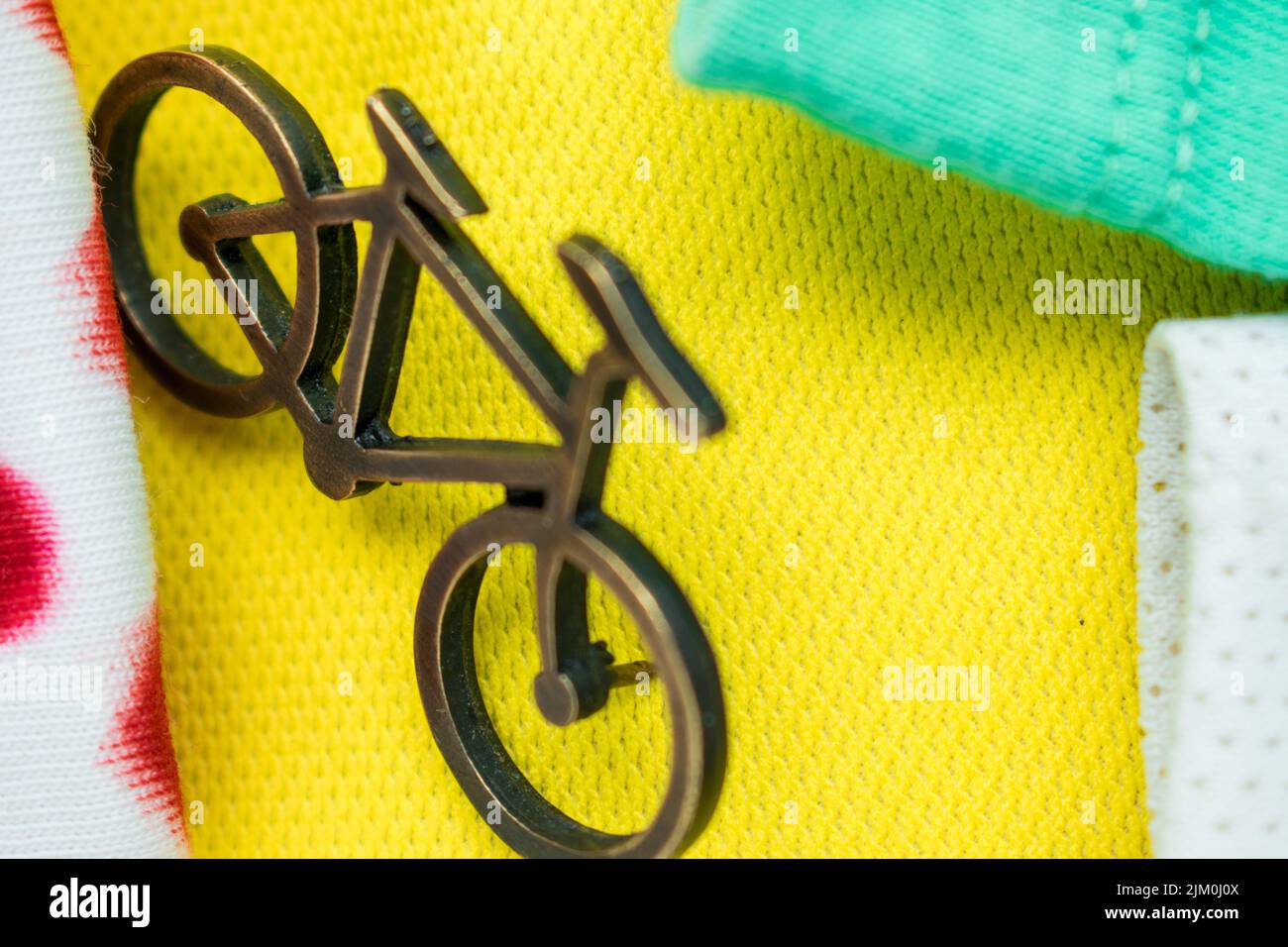 Un primo piano di un piccolo spilla per bicicletta su una t-shirt gialla, verde e bianca per il tour della Francia Foto Stock