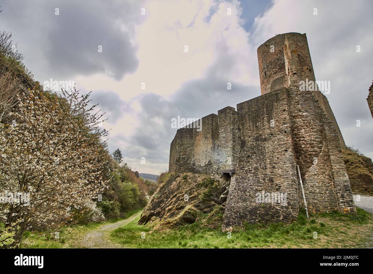 Uno scatto verticale delle rovine del castello di Lowenburg a Monreal Eifel in Germania con un cielo nuvoloso blu Foto Stock