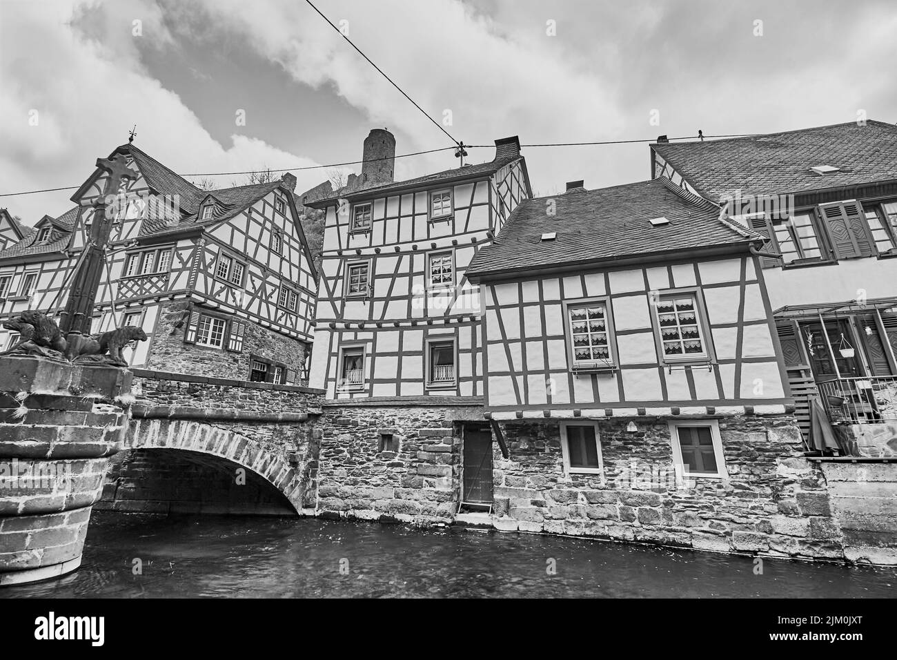 Un colpo in scala di grigi di case ed edifici a Monreal, Germania, su un ponte fluviale con un cielo grigio nuvoloso Foto Stock