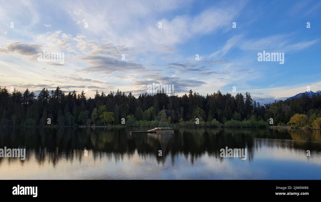 Una vista mozzafiato della Lost Lagoon, lo Stanley Park sullo sfondo blu del cielo nuvoloso Foto Stock