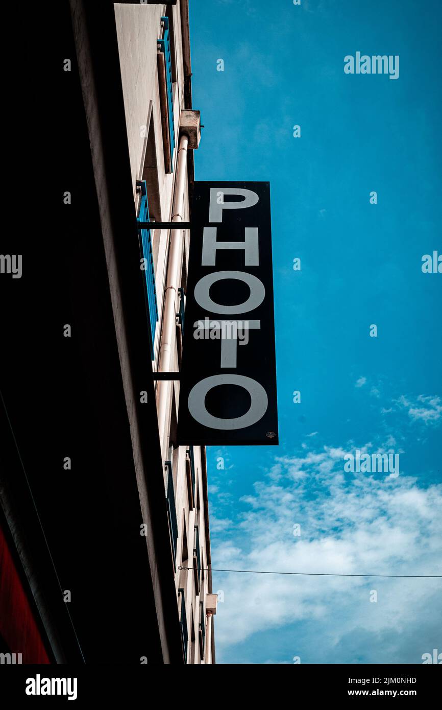 Uno scatto verticale di un cartello su un edificio che dice 'FOTO' su uno sfondo di un cielo nuvoloso blu Foto Stock