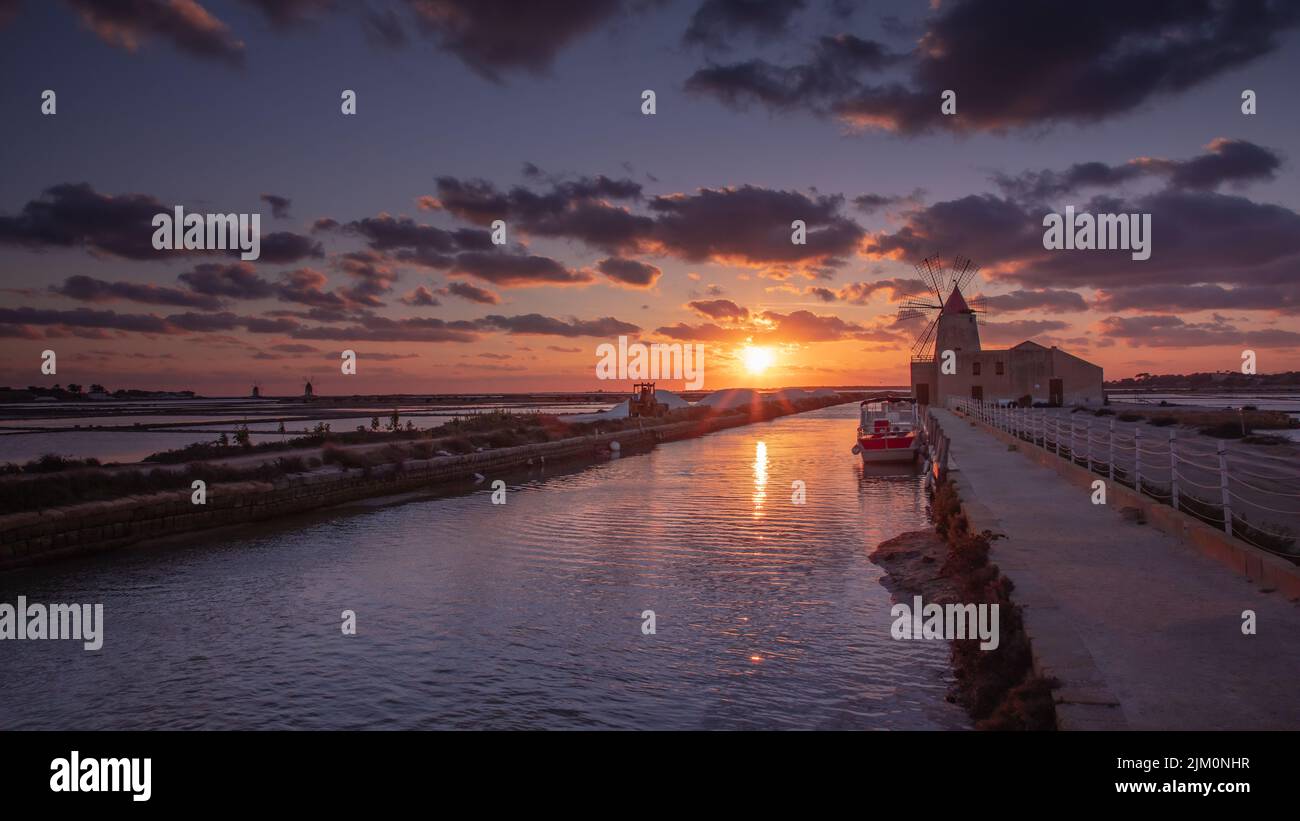 Il Mar Mediterraneo riflette i bellissimi colori del tramonto a saline della laguna di marsala, Italia Foto Stock