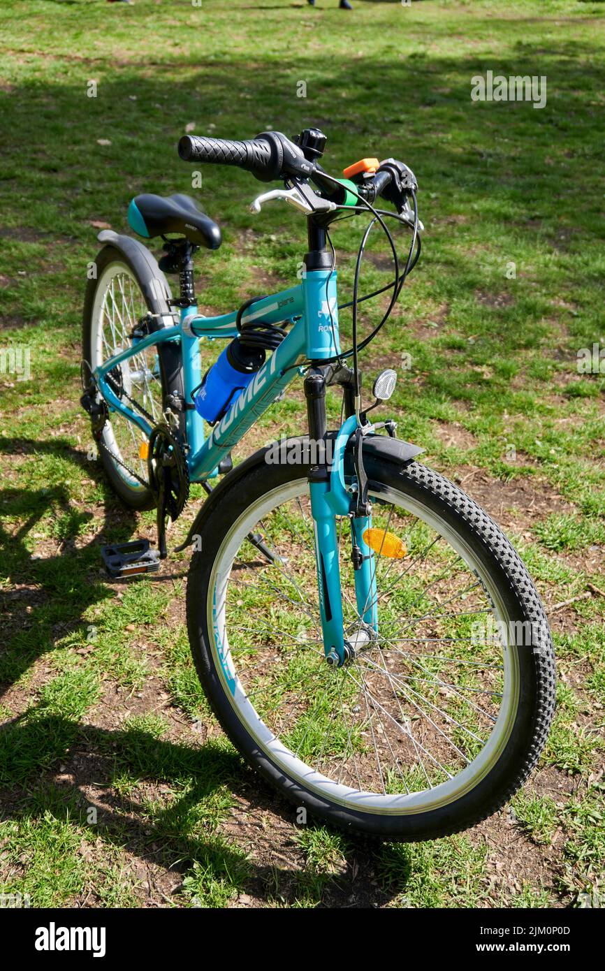 Una bicicletta blu per bambini in piedi su erba verde in un parco in una giornata di sole Foto Stock