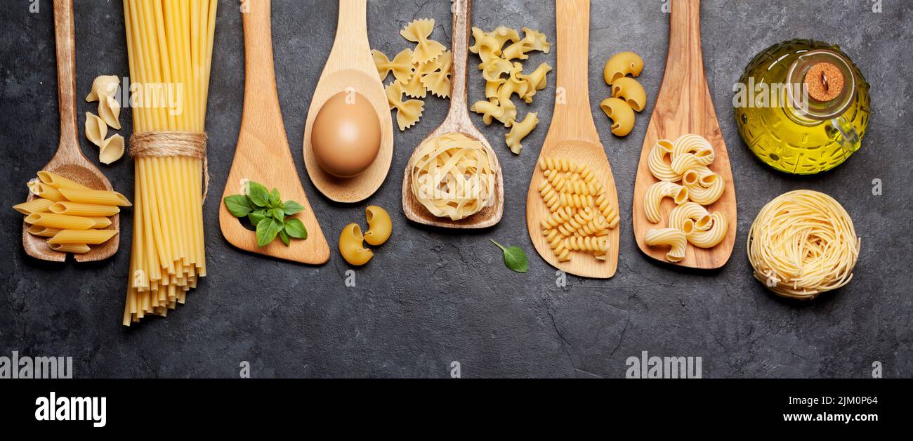 Pasta varia in cucchiai di legno. Vista dall'alto, disposizione piatta Foto Stock