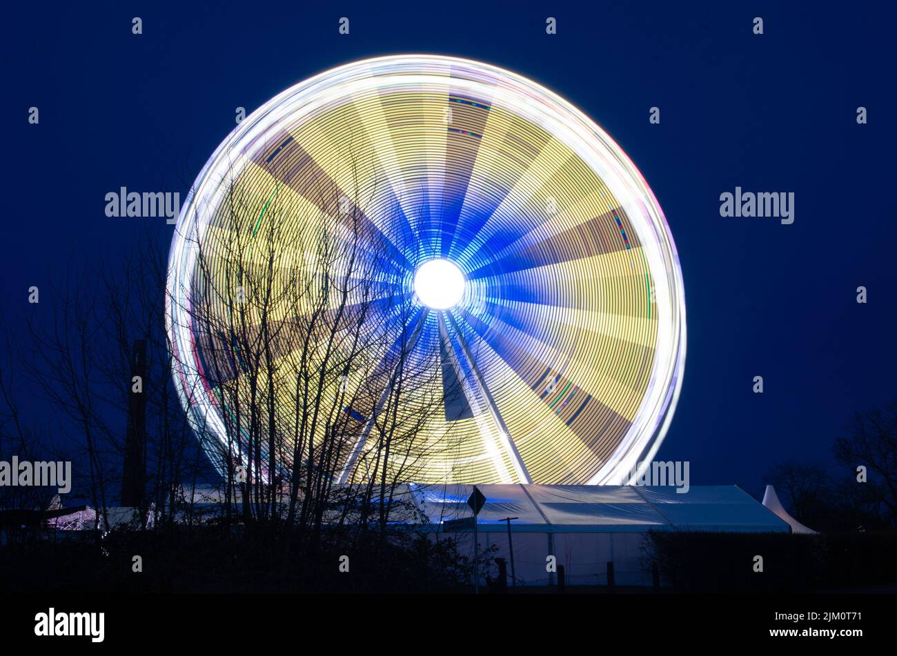Un colpo sfocato di una grande ruota panoramica che si muove di notte con luci luminose che ne escono Foto Stock