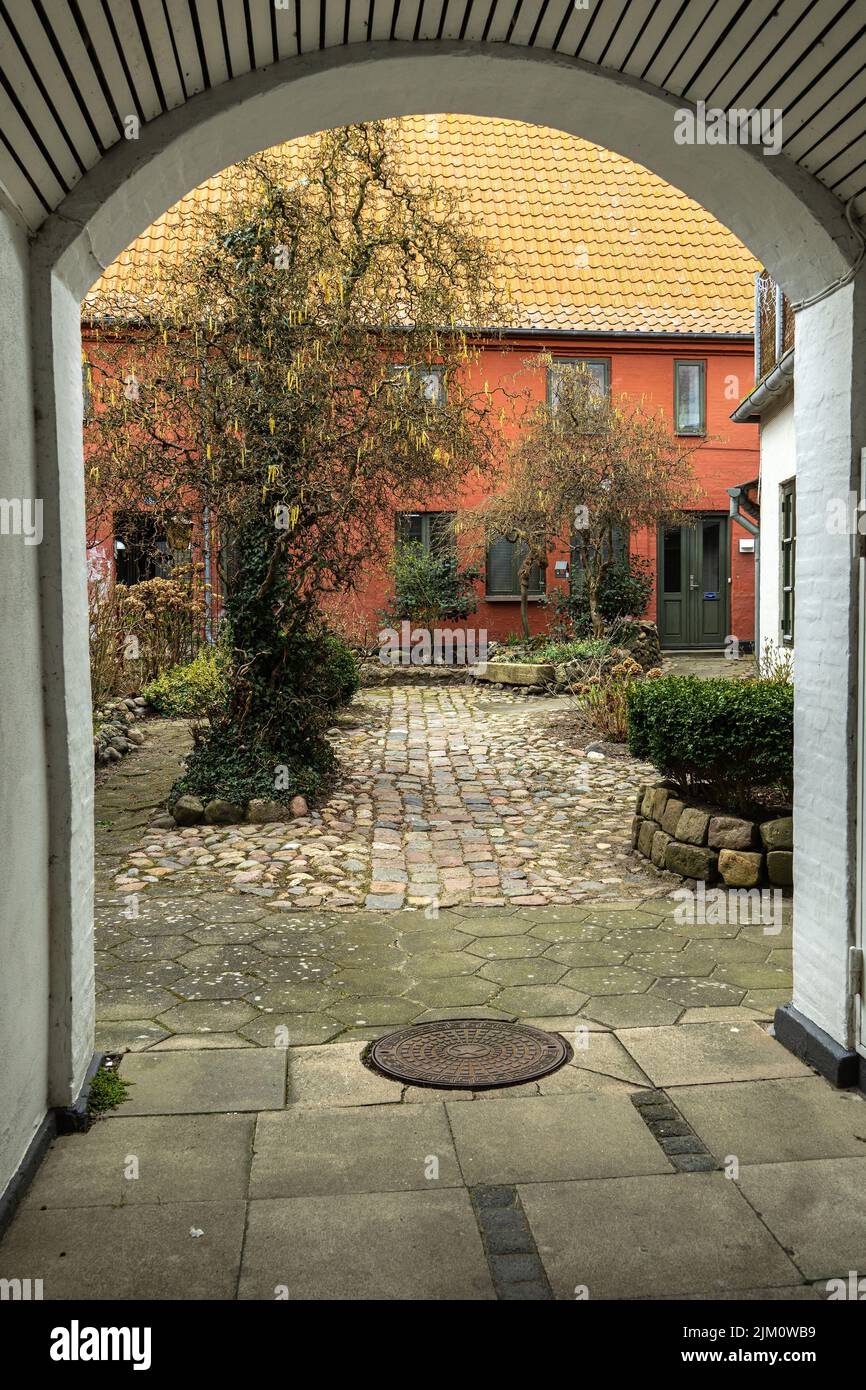 Tipico cortile con giardino visto da un passaggio coperto nella città di Assens. Assen, Fyn, Danimarca, Europa Foto Stock