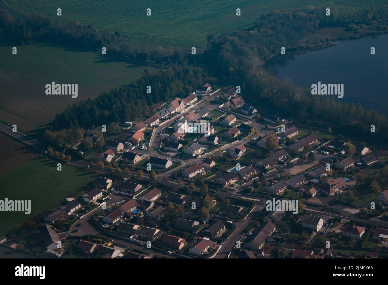 Una vista dall'alto di un quartiere residenziale con case circondate da un lago e dal verde Foto Stock