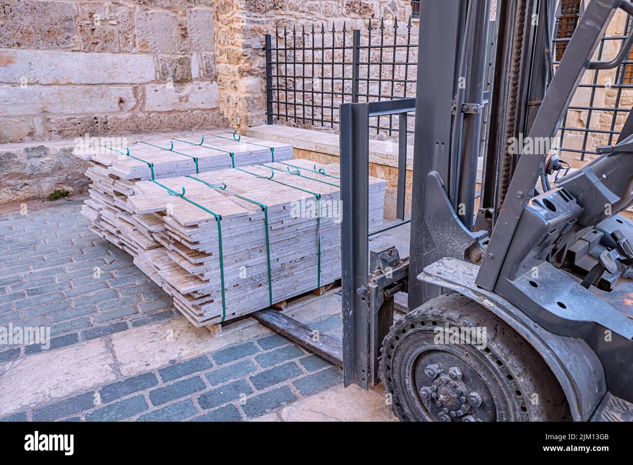 Carrello elevatore che lavora con piastrelle di carico in cantiere o magazzino. Attrezzatura industriale e concetto di veicolo Foto Stock