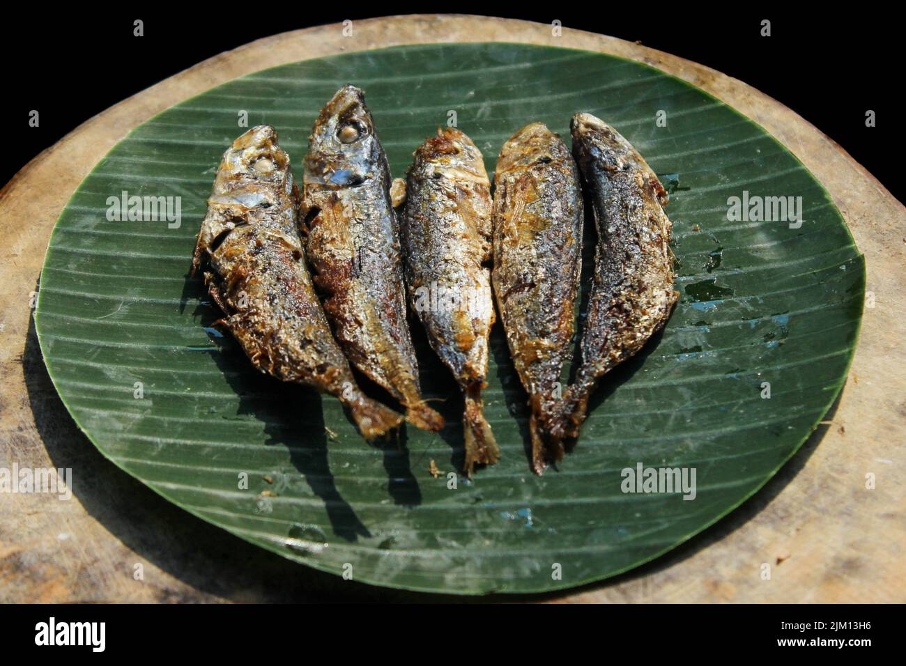 cibo indonesiano autentico fritto pesce salato o ikan asin gereh su superficie di legno con foglia di banana. Foto Stock