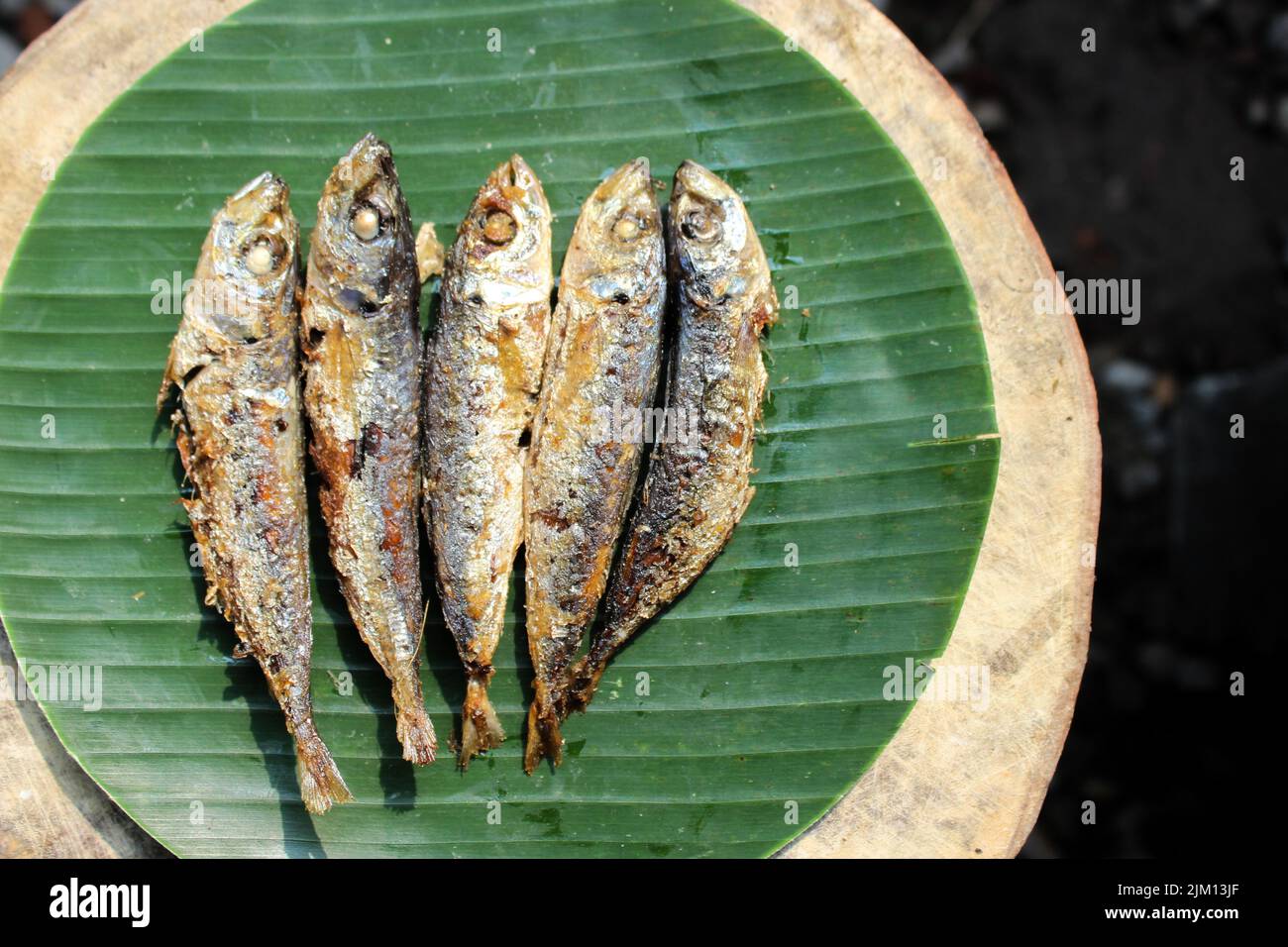 cibo indonesiano autentico fritto pesce salato o ikan asin gereh su superficie di legno con foglia di banana. Foto Stock