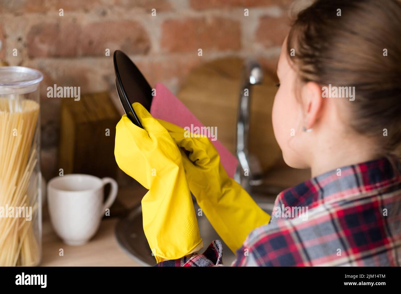 piccolo aiutante giovane ragazza lavare piatti guanti gialli Foto Stock