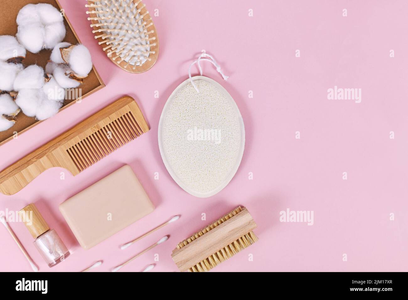 Prodotti ecologici per la bellezza e l'igiene del legno come pettine e sapone su sfondo rosa Foto Stock
