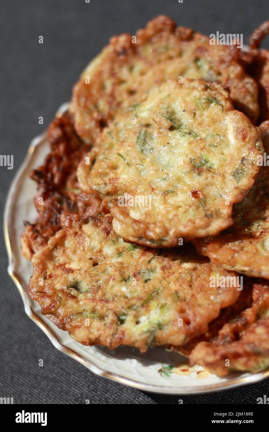Frittelle di verdure a base di zucchine appena cucinate a primo piano. Profondità di campo poco profonda Foto Stock