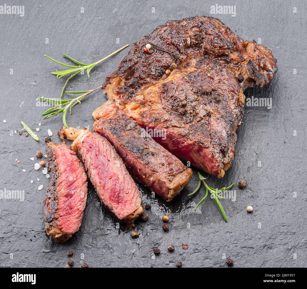 Bistecca di ribeye mediamente rara alla griglia su piastra di pietra grigia. Foto Stock