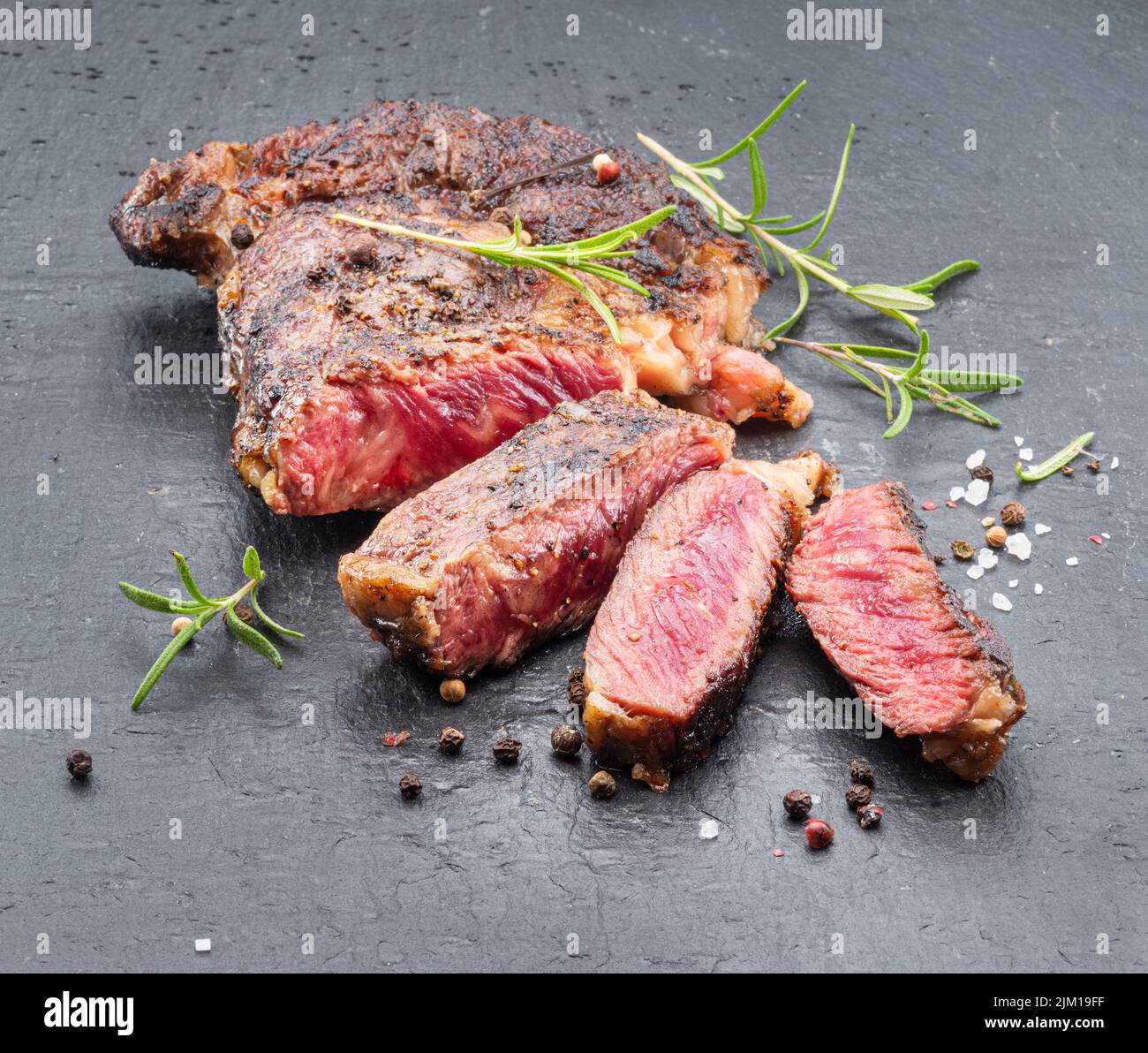 Bistecca di ribeye mediamente rara alla griglia su piastra di pietra grigia. Foto Stock