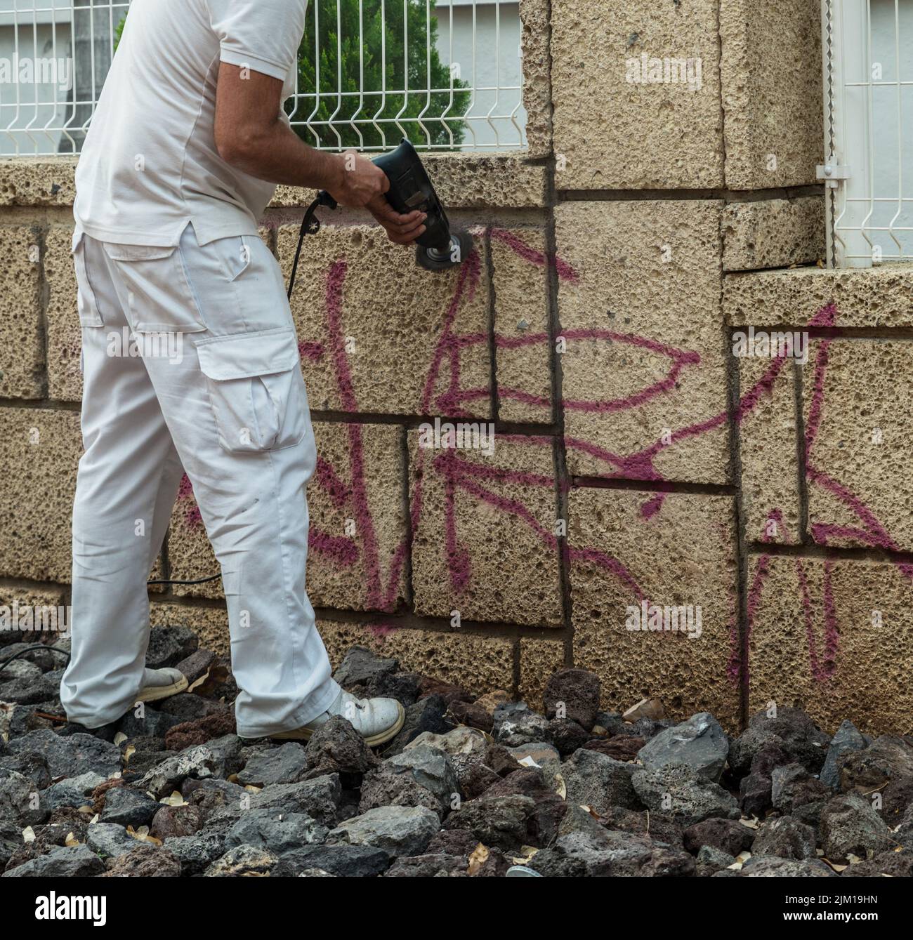 Operatore che rimuove i graffiti dalla parete daubed. Foto Stock