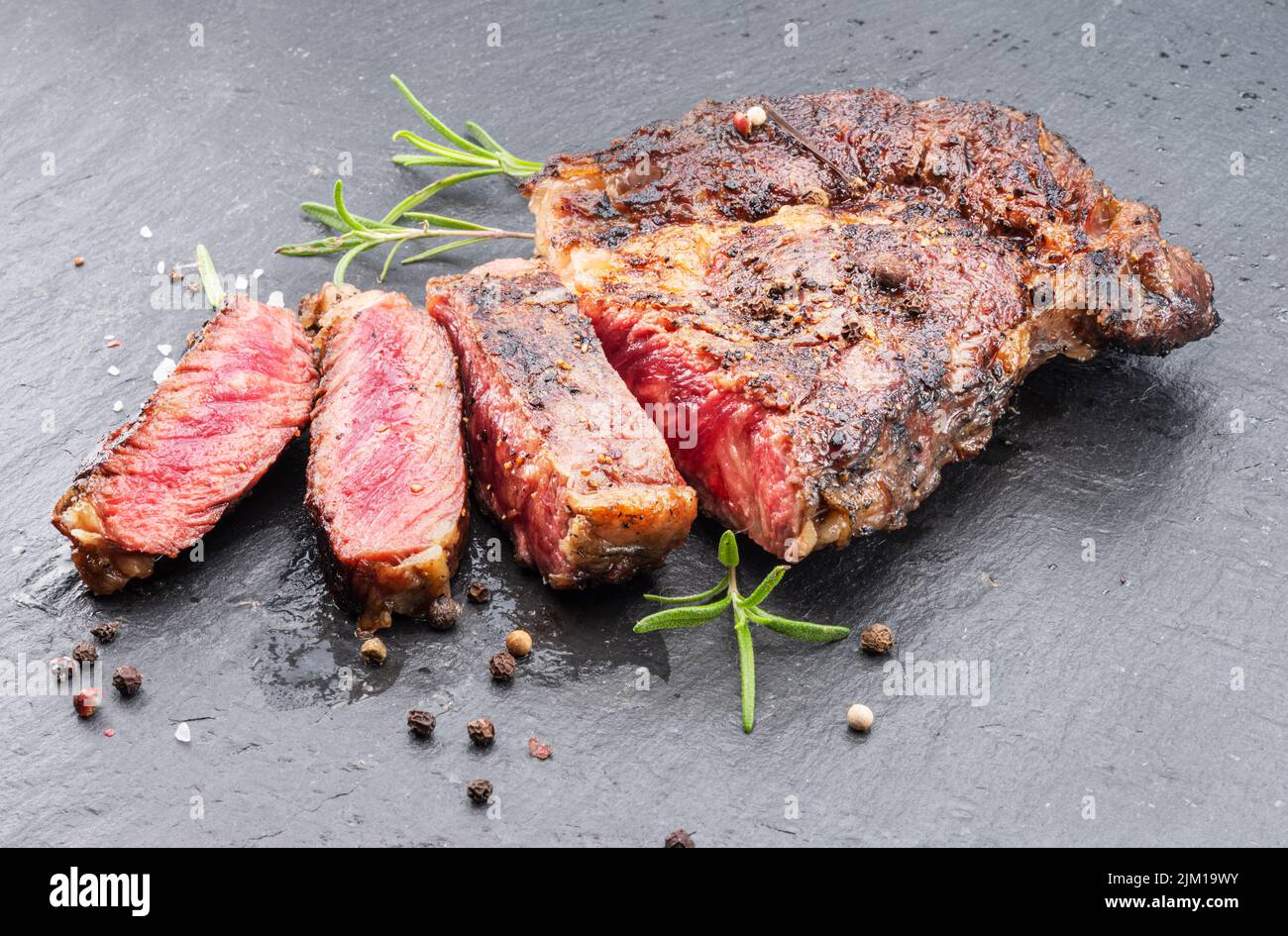 Bistecca di ribeye mediamente rara alla griglia su piastra di pietra grigia. Foto Stock