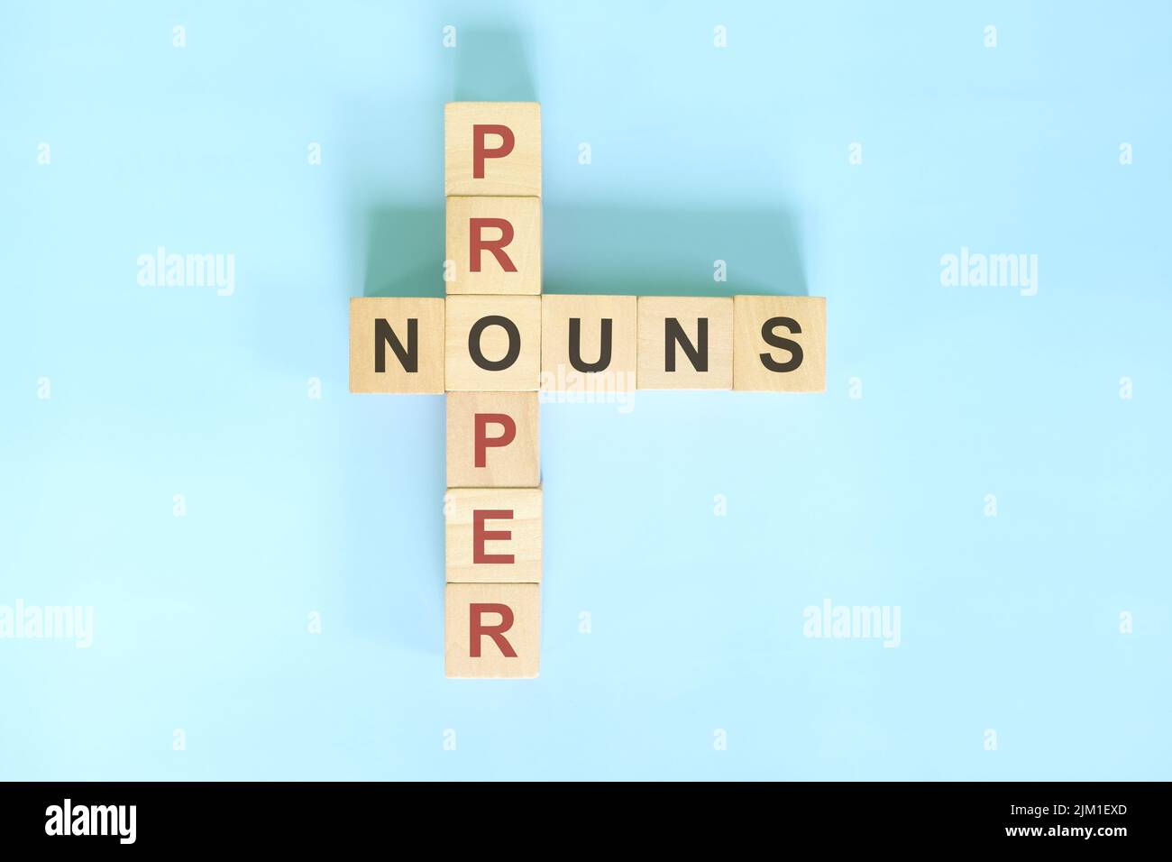 Concetto di sostantivi nella formazione grammaticale inglese. Blocco di legno Crossword puzzle piatto adagiare su sfondo blu. Foto Stock