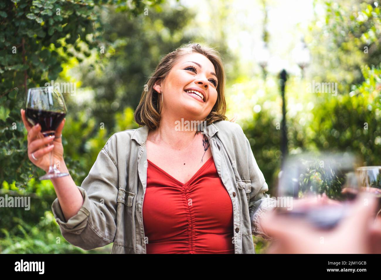 Felice giovane donna con un bicchiere di vino rosso - ritratto di una ragazza curvilinea positiva che tiene un wineglass e godersi la vita in campagna - la gente vive Foto Stock