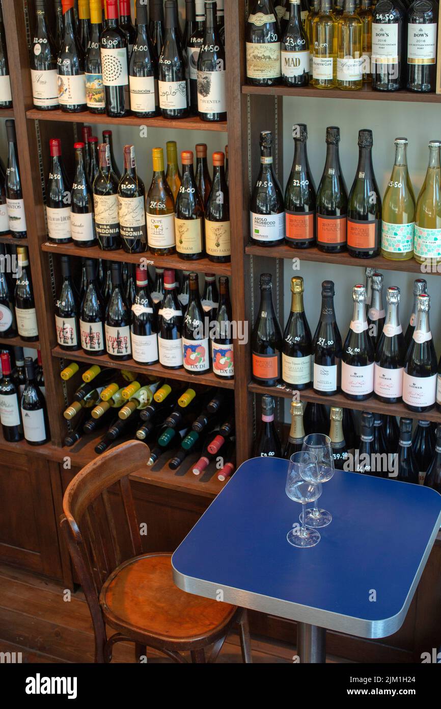 vista sul bicchiere di vino con bottiglie negli scaffali di un negozio di vini Foto Stock