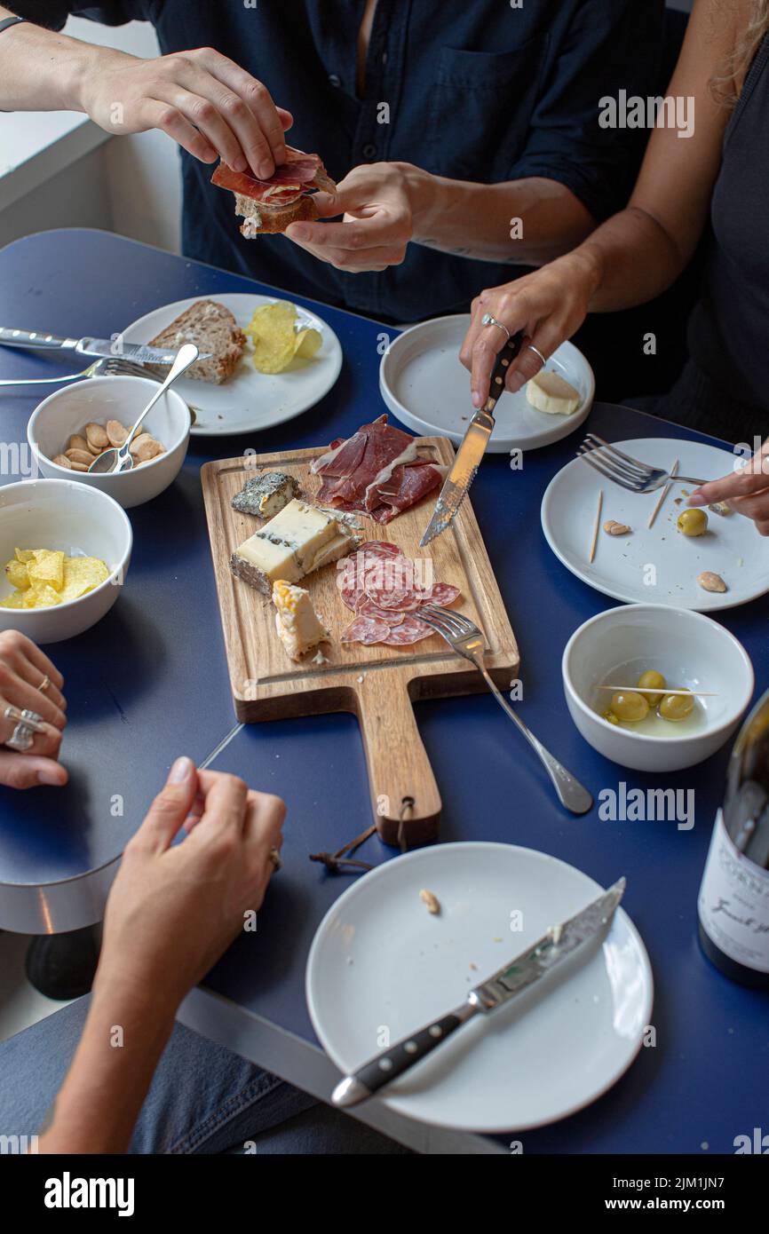 salumi e formaggi a tavola, vino rosso, spuntini e le mani dei popoli Foto Stock