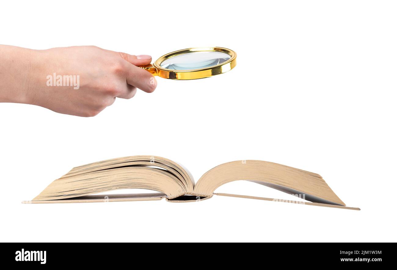 Mano che tiene la lente di ingrandimento sopra il libro aperto isolato su sfondo bianco. Concetto di studio e istruzione. Condurre ricerche, analisi delle informazioni, ricerca dei dati. Foto di alta qualità Foto Stock