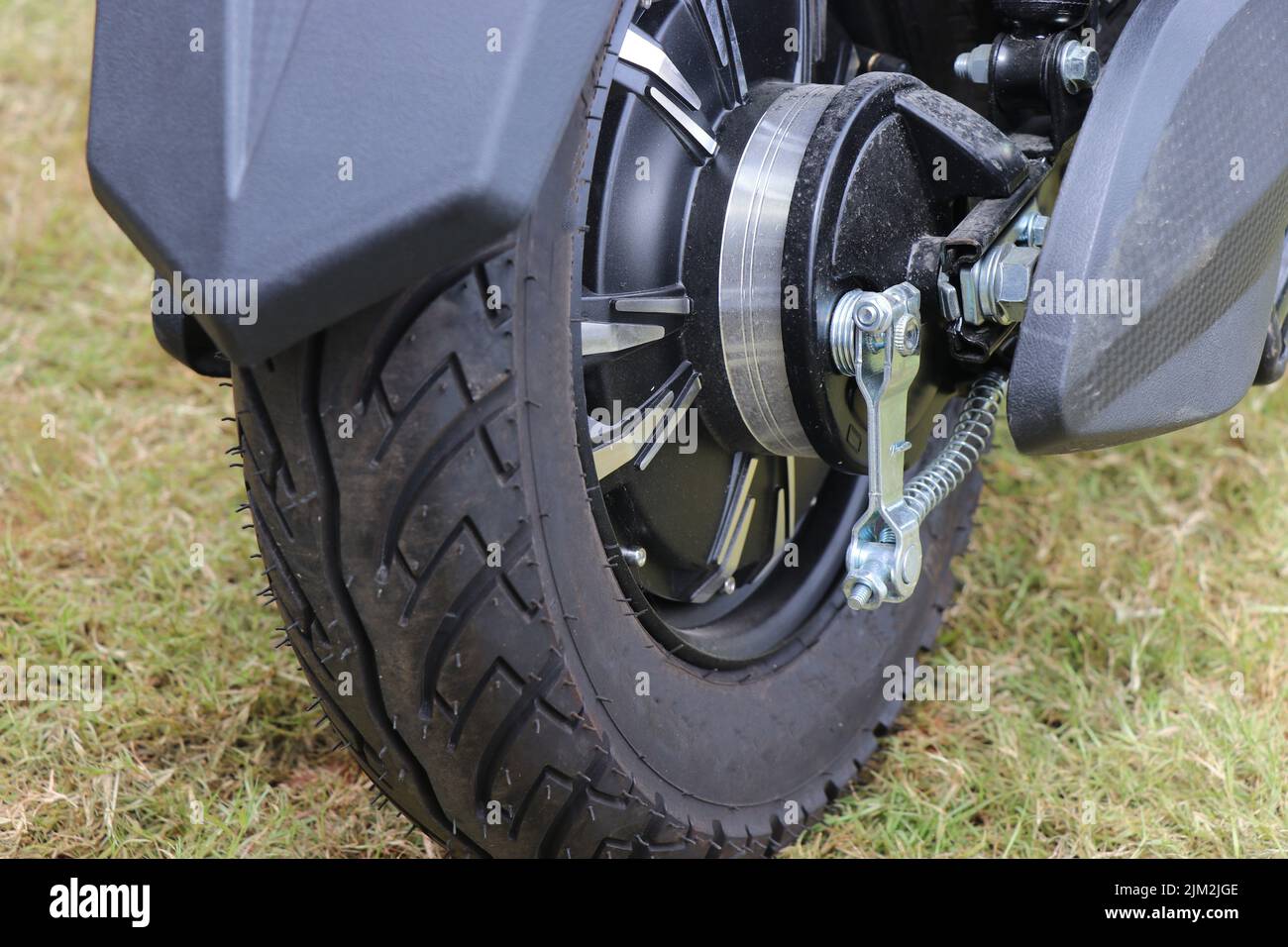 Ruote in gomma collegate ad un motore brushless su un veicolo elettrico con vista posteriore del veicolo in piedi su un prato Foto Stock