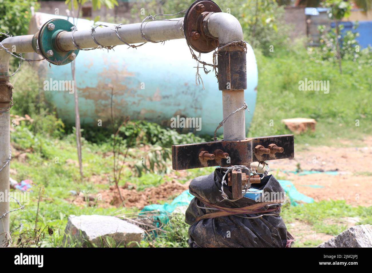 Pompa dell'acqua sommergibile collegata a tubi metallici e supporti arrugginiti alla luce del giorno Foto Stock