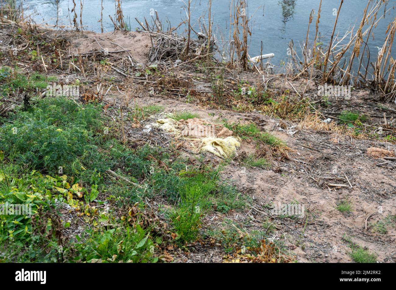 I rifiuti di plastica sono in parte sepolti nella riva sabbiosa del fiume Severn a Shrewsbury. Foto Stock