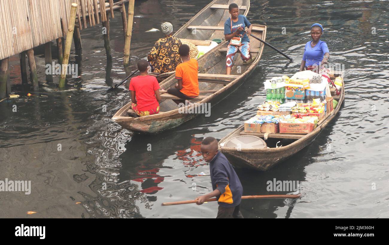 Una donna si siede in una canoa mentre vende cibo ai residenti di makoko nella comunità di pescatori di Makoko sulla laguna di Lagos. Makoko è una comunità di slum situata a Lagos. Fondata nel 18th secolo principalmente come villaggio di pescatori, gran parte di Makoko è composta da strutture costruite su palafitte, ai margini della laguna di Lagos. Nigeria. Foto Stock