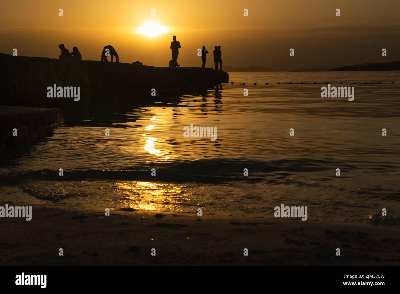 Silhouette di persone su un molo al tramonto. Foto Stock