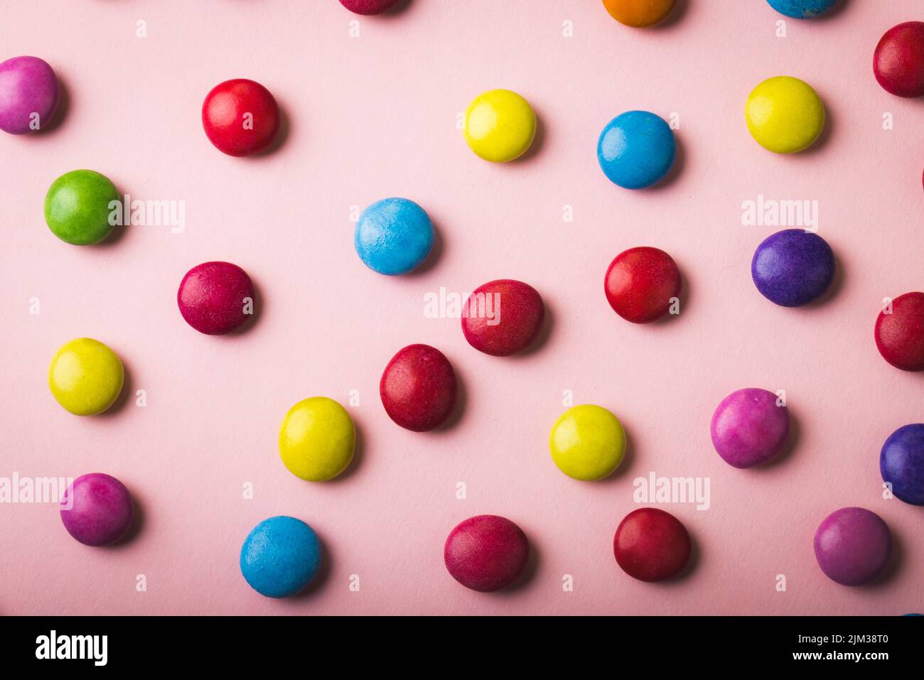 Direttamente sopra la vista di caramelle al cioccolato multicolore sparse su sfondo rosa Foto Stock