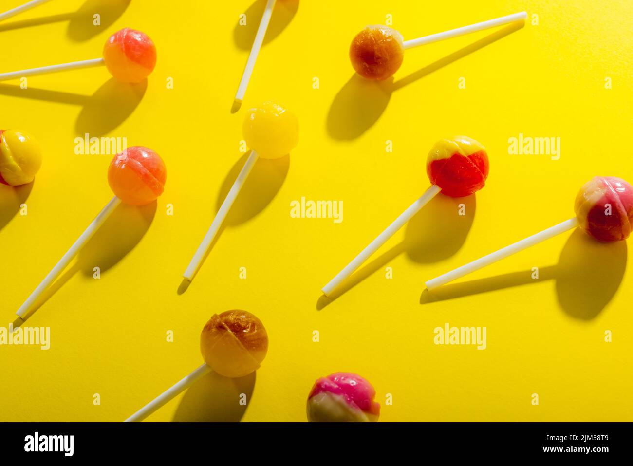 Vista dall'alto dei lollipop sparsi su sfondo giallo Foto Stock
