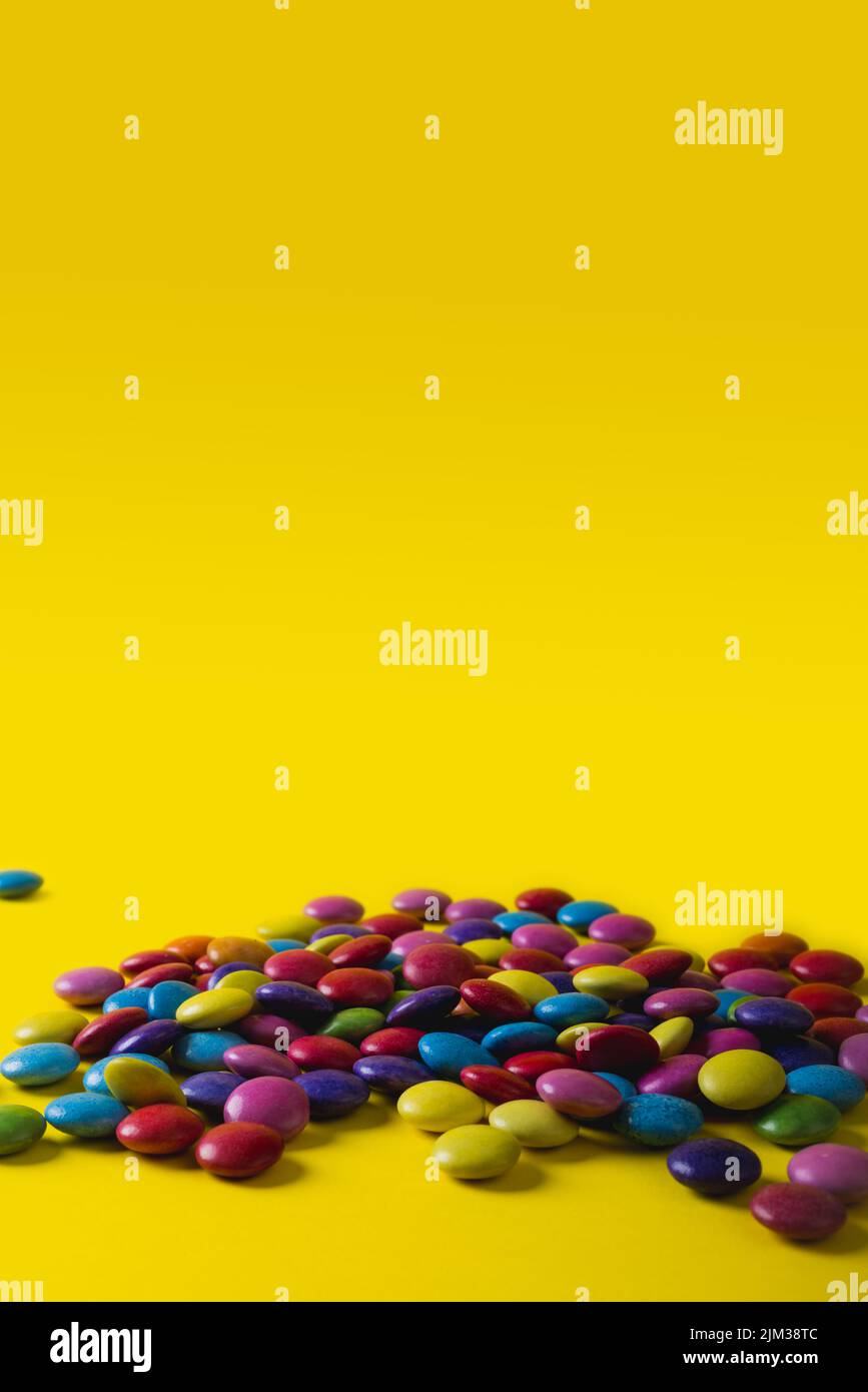Pile di caramelle colorate al cioccolato con spazio copia su sfondo giallo Foto Stock