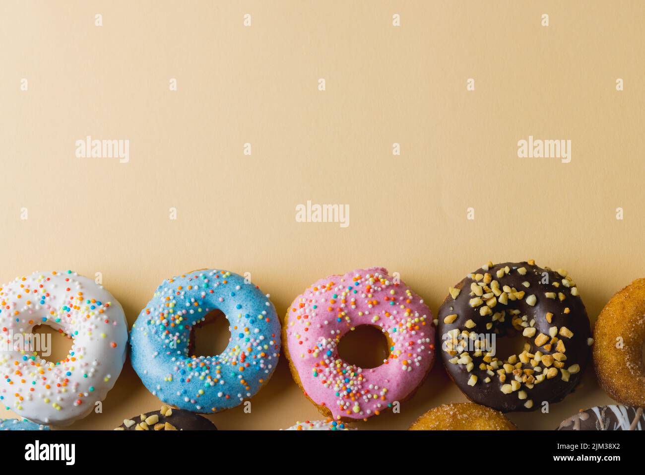 Direttamente sopra la vista di ciambelle fresche con spruzzatori disposti da spazio copia su sfondo beige Foto Stock