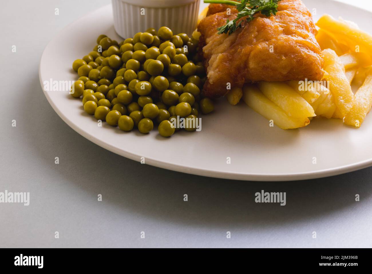 Primo piano di patatine fritte con frutti di mare e piselli in piatto, spazio copia Foto Stock