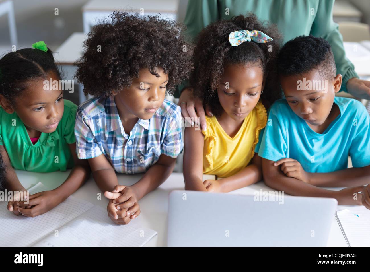 Studenti elementari afroamericani che cercano un computer portatile mentre sono seduti alla scrivania durante una lezione di computer Foto Stock