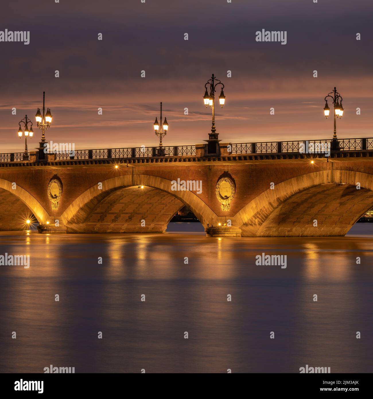 Lunga esposizione del Pont de Pierre che attraversa il fiume Garonna nella città di Bordeaux, la Francia illuminata subito dopo il tramonto Foto Stock