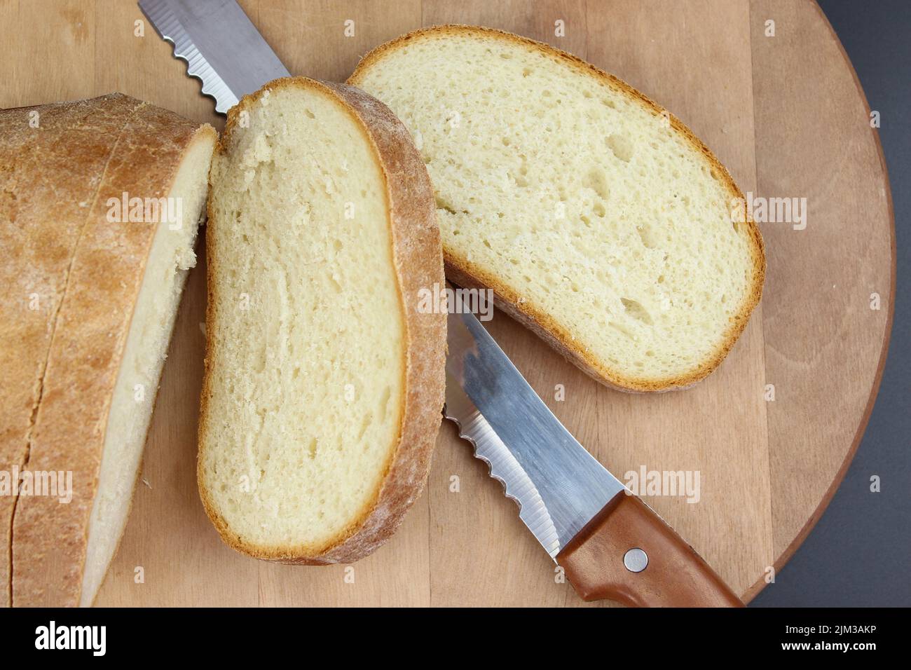 Piatto di pane appena sfornato e fette di pane su rustico asse di legno. Foto Stock