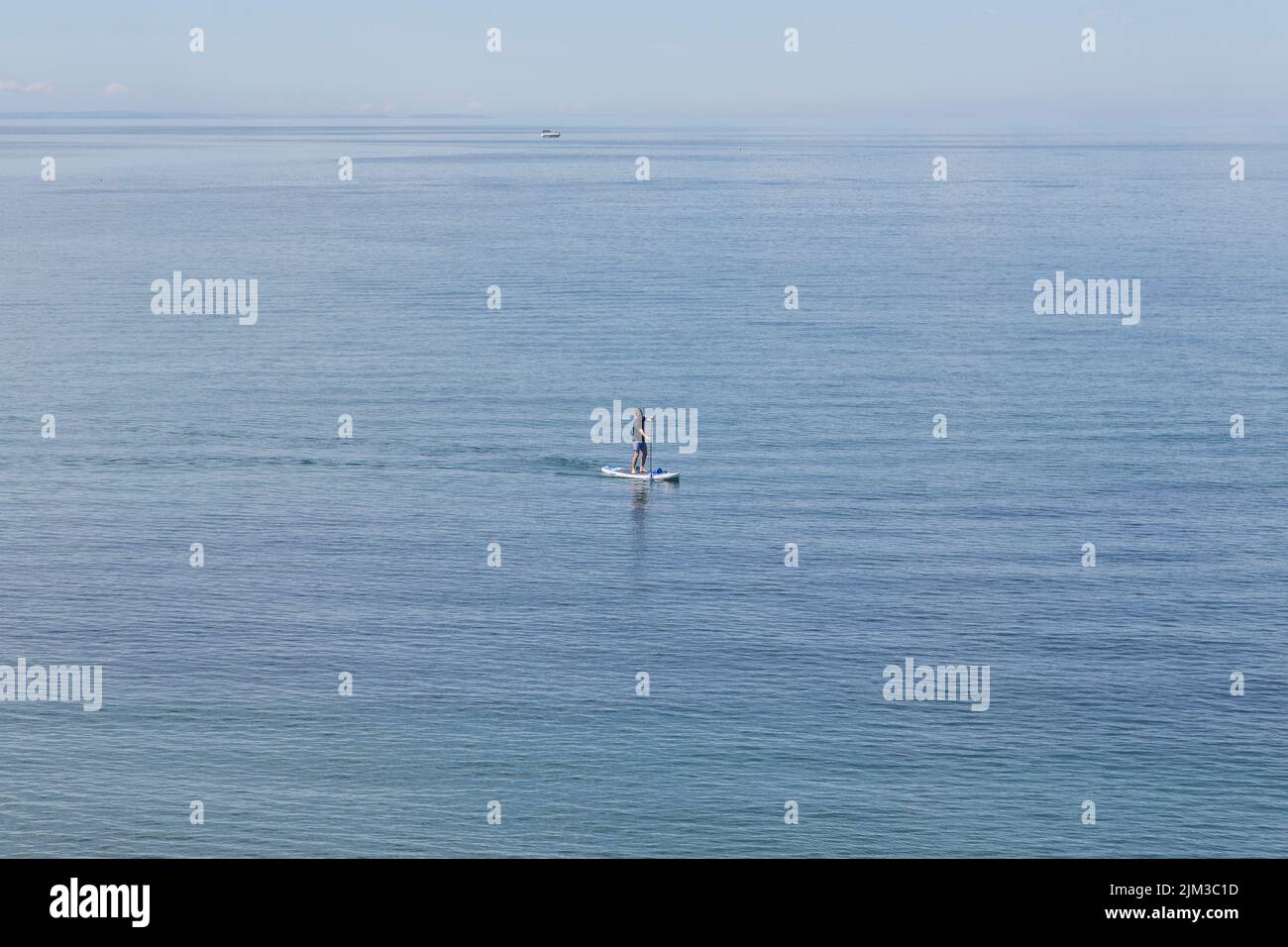 Un uomo paddle boarding in mare. Salute, fitness, vacanza, ricreazione, tempo da solo concetto. Foto Stock