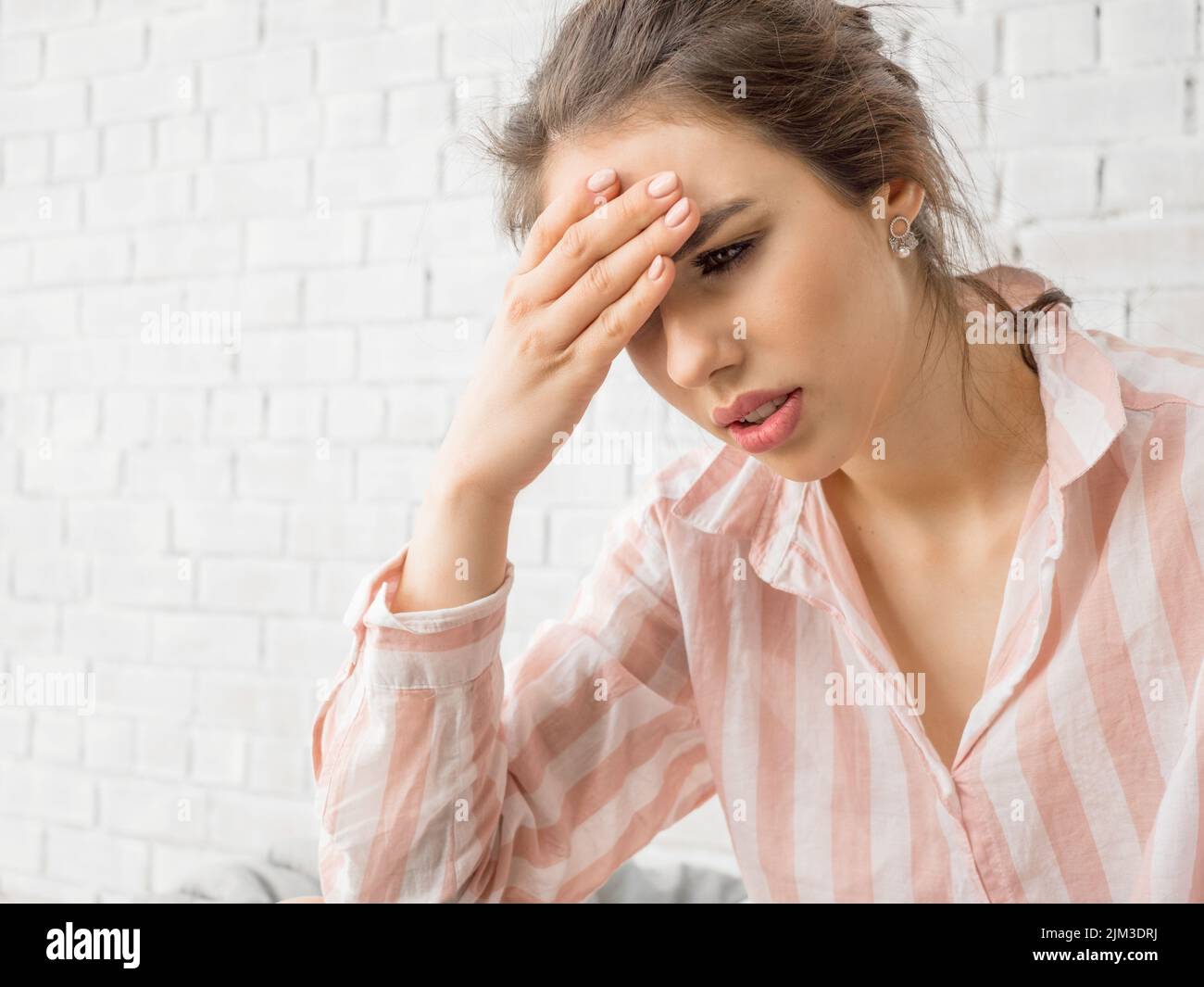 Foto da vicino di una donna con grave mal di testa. Tiene la fronte e cerca di affrontare il dolore. Foto Stock