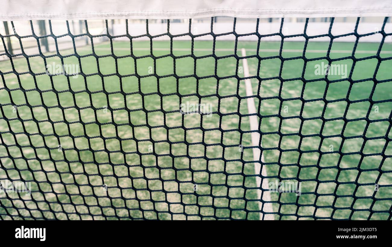 Rete e una parte di verde erba sintetica paddle campo da tennis al coperto senza persone. Paddle è un gioco di racquetball. Concetto sportivo professionale con copia spac Foto Stock