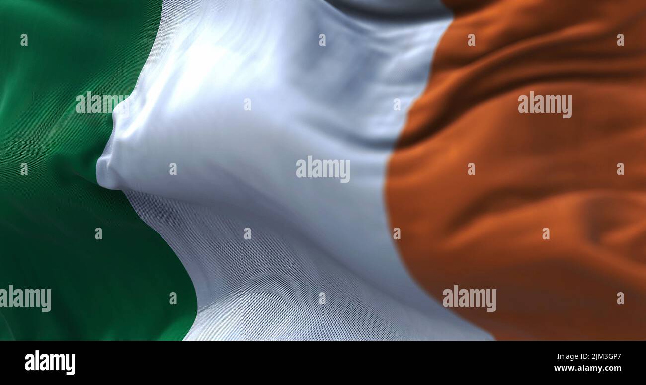 Vista ravvicinata della bandiera nazionale irlandese che sventola nel vento. L'Irlanda è un'isola nell'Oceano Atlantico settentrionale, nell'Europa nord-occidentale. Tessitura del tessuto Foto Stock