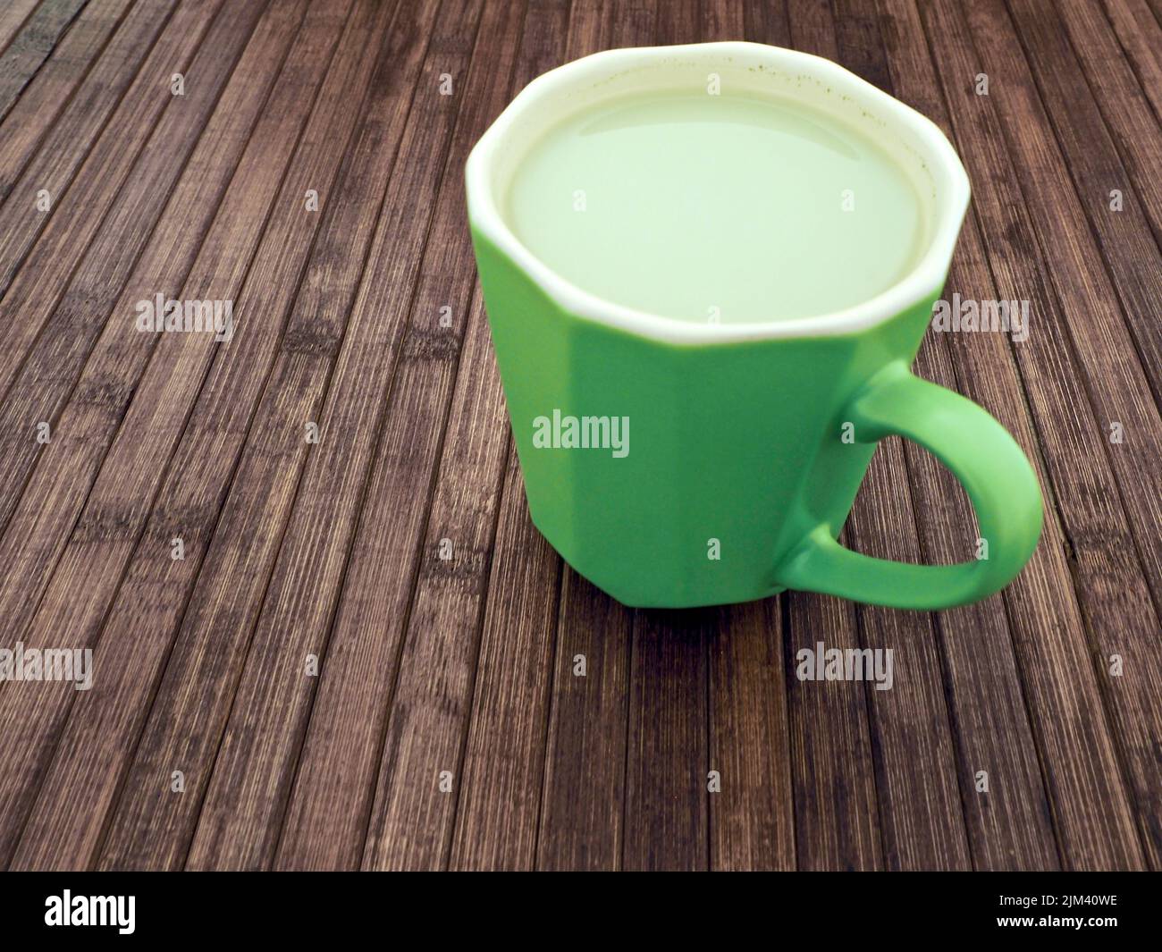 vista ravvicinata di un latte di mandorla in una tazza verde su un tavolo di legno Foto Stock vista ravvicinata di un latte di mandorla in una tazza verde su un tavolo di legno Foto Stock