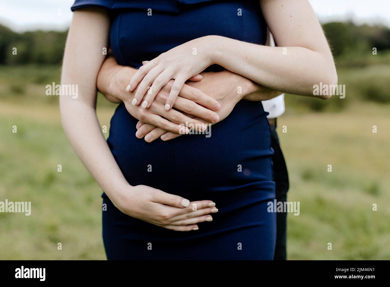 Un colpo di primo piano dei futuri genitori che abbraccia una pancia incinta di 38 settimane Foto Stock